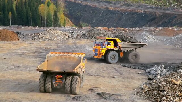 Large yellow dump trucks operating in a vast open pit coal mine excavation site truck mining heavy industry