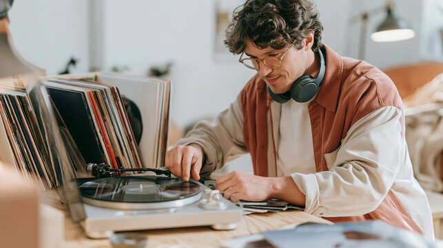 Man enjoying music hobby, listening to vinyl records on a turntable at home, selecting tracks