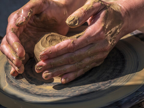 Potter Shaping Clay on a Spinning Wheel, Hands-On Pottery Making at an Outdoor Workshop
