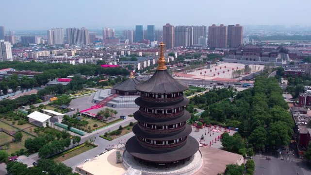 Aerial view combining an ancient multi-tiered pagoda with modern city high-rise buildings and green urban spaces.