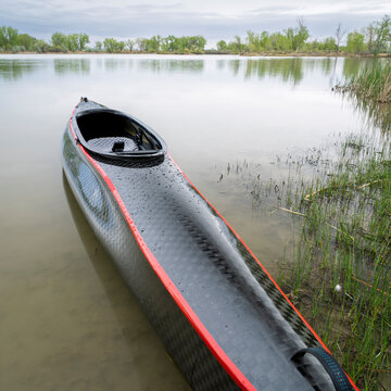 decked touring canoe with carbon fiber hull and rudder at a shore of Horsetooth Reservoir - early spring scenery of Colorado foothills