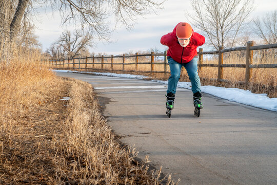 senior male is inline skating on a paved bike trail along Poudre River in Colorado, fall or winter scenery at sunset