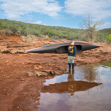 senior paddler is launching his decked touring canoe on shore of Horsetooth Reservoir - early spring scenery of Colorado foothills
