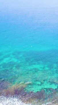 Vertical aerial view of the turquoise sea at Anse Fourmis in Seychelles showing crystal clear water, tropical coastline and scenic Indian Ocean scenery.