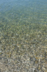 Clear shallow water over smooth pebbles with sunlight ripples and calm texture © Waldemar