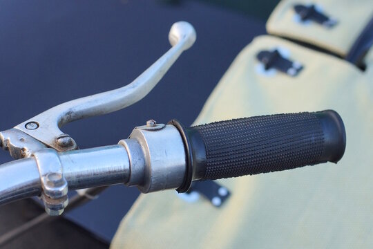 part of a old motorcycle with black gray steering wheel on the summer street