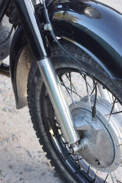 one gray black wheel on a motorcycle fork on a gray background on a summer city street