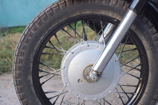 one gray black wheel on a motorcycle fork on a gray background on a summer city street
