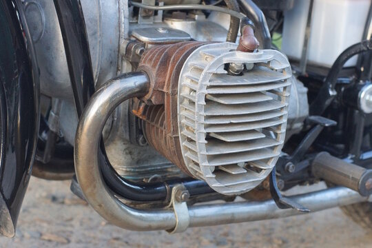 part of one old motorcycle with gray iron radiator and carburetor on summer street