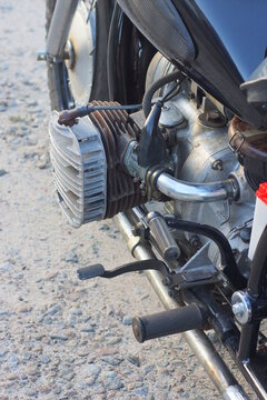 part of one old motorcycle with gray iron radiator and carburetor on summer street