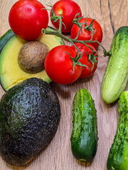 Healthy food corner with avocado, tomatoes and cucumbers on wooden background with copy space © Lona