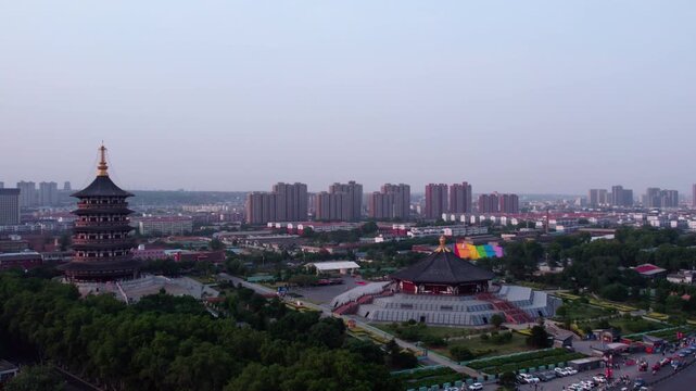 Aerial view of traditional ancient structures and modern high-rise buildings in an urban area under a hazy sky.