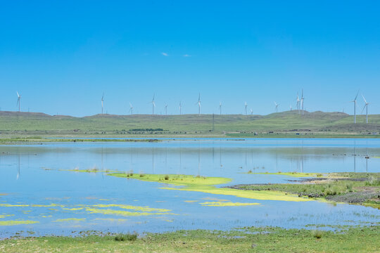 Scenic landscape of salt lake wetland and distant wind turbines in summer in Ulan Hada Volcano Geopark, Ulanqab, Inner Mongolia, China