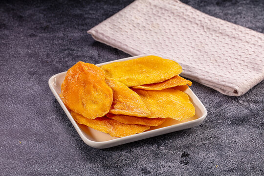 Dried mango slices on white plate with textured napkin