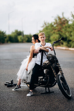A couple of newlywed freaks on a black custom bike