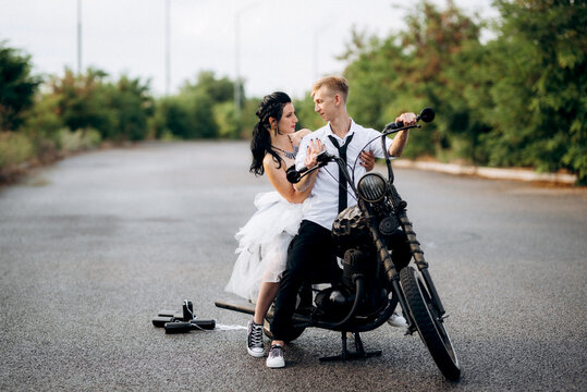 A couple of newlywed freaks on a black custom bike