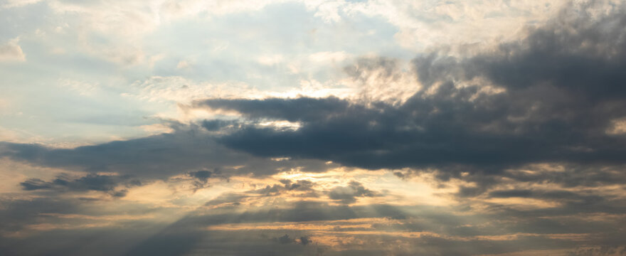 Dramatic sky with sun rays through dark clouds at day's end
