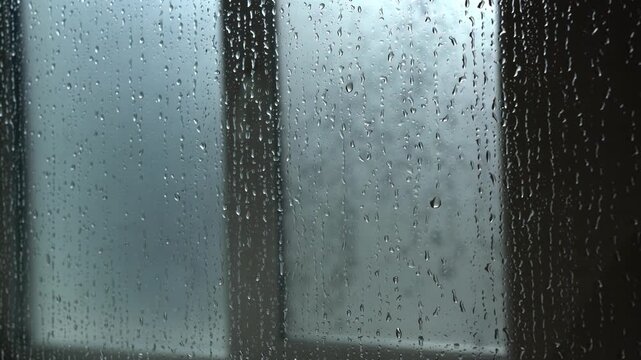 Raindrops falling on a window glass pane during a storm