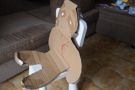 Homemade Cardboard Craft Figure Attached to a Small Chair Indoors