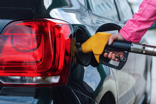 Close-up of refueling a car with yellow nozzle at gas station. Concept of fuel crisis, expensive petrol, rising energy prices, inflation, and high cost of driving