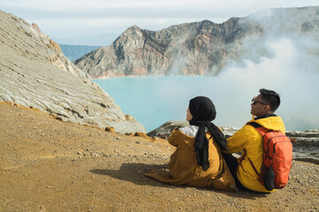 Couple Sitting at Volcanic Crater Lake Edge Enjoying Misty Mountain View and Adventure © Alfian Muzaki