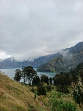 Vertical View of Segara Anak Lake Surrounded by Misty Volcanic Mountains on Mount Rinjani Trail, Lombok Indonesia