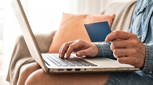 Man holding credit card typing on laptop for online payment at home