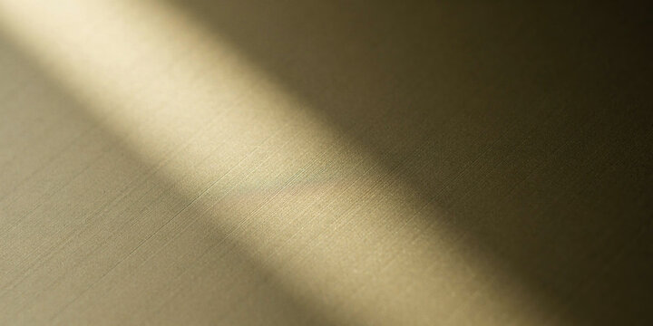 Golden brushed brass texture with soft diagonal light beam.