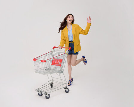 Asian Woman pushing shopping cart and waving celebrating retail shopping consumer confidence seasonal sales smart spending promotions and joyful modern lifestyle.
