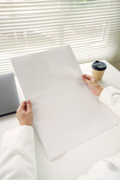 Blank poster mockup held by professional at office desk with laptop providing copy space for advertising presentation branding business communication and creative campaign design.