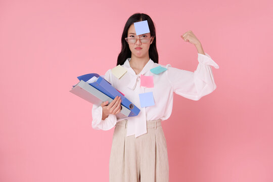 Asian businesswoman holding office folders with sticky notes showing determination to overcome workload pressure multitasking stress deadlines resilience productivity and workplace challenge.
