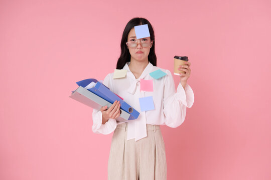 Asian businesswoman holding folders and coffee with sticky notes expressing work overload burnout deadline pressure multitasking stress low energy and need for workplace balance.