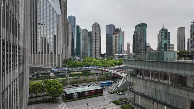 A daytime view of a modern urban district with high-rise buildings, roads, green spaces and pedestrian overpasses.