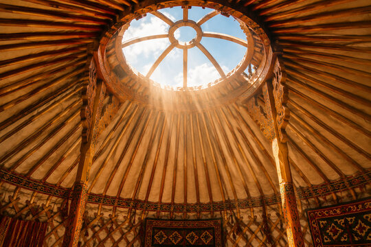 Interior upward view of a traditional yurt with sunlight through the roof opening.