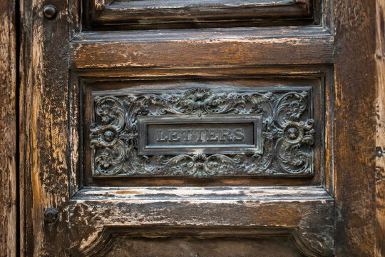 Aged wooden door with an ornate metal plaque inset in the center.