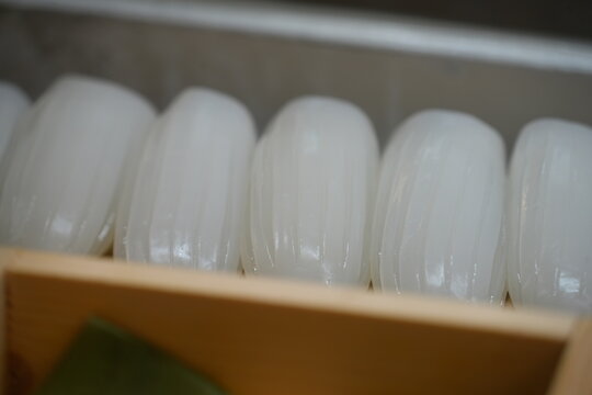 Fresh raw squid sushi slices displayed neatly in a box.