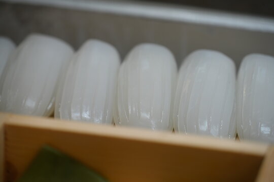 Fresh raw squid sushi slices displayed neatly in a box.