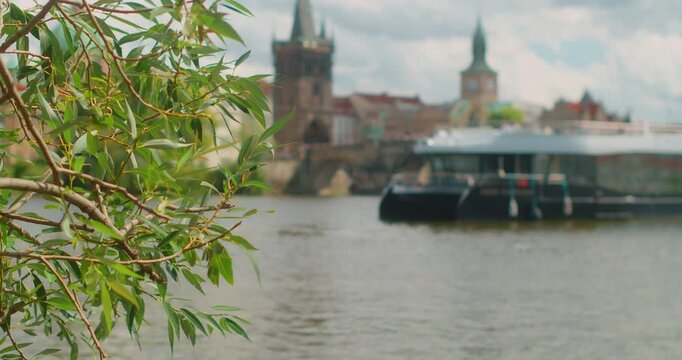 Blurred view of cruise boat on the Vltava River in Prague with historic architecture and waterfront scenery. Charles Bridge during a calm summer travel day.
