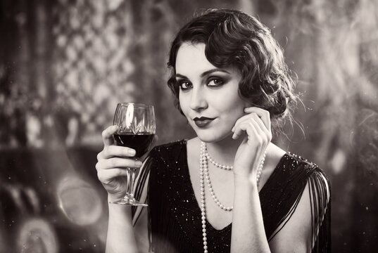 Elegant flapper girl holding a wine glass in a vintage 1920s style portrait.