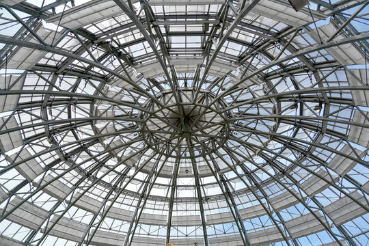 View from below highlights the intricate design of a dome made of metal and glass. Natural light fills the space on a sunny day