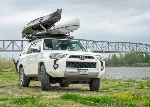 Brownville, NE, USA - April 23, 2026: Toyota 4Runner SUV with canoes on roof racks and a bike on a shore of the Missouri River.