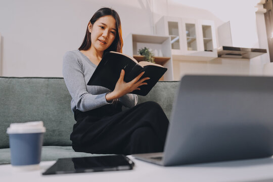 Young woman reading book on sofa at home