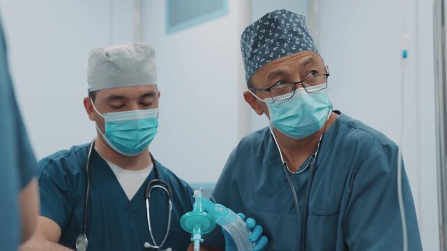 Medical team administers general anesthesia and supports patient breathing with a manual ventilation bag in the operating room before a surgical procedure