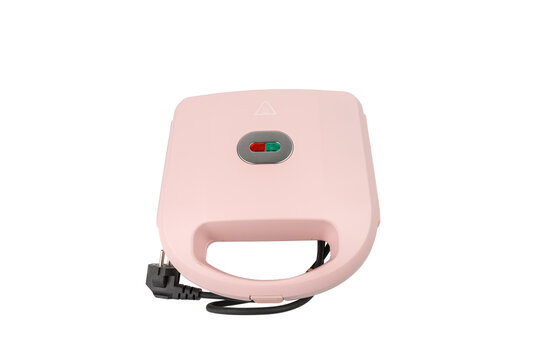A closed pink sandwich toastie maker with a red and green power indicator light stands on a plain white background.