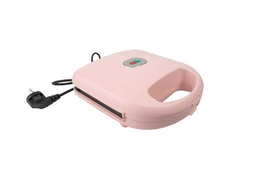 A closed pink sandwich toastie maker is shown at a three-quarter angle with its black cord and two-pin plug visible on white background.
