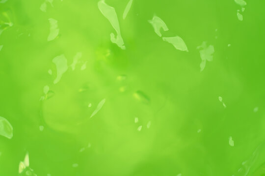 Macro shot of green aloe vera gel texture with air bubbles and light reflections, selective focus with copy space on green background for skincare cosmetics, hydration, and organic beauty products.