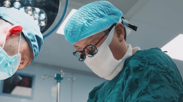 Surgeons perform tissue cauterization during an operation as surgical smoke rises from the operating field. Medical team works with precision in a hospital operating room