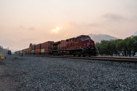 Banff, Canada - August 09, 2026: Canadian Pacific freight train carrying stacked shipping containers through Banff railway station in the Canadian Rockies.