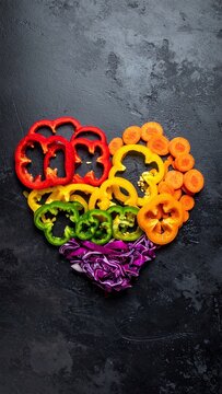 A vibrant heart shape crafted from fresh, sliced vegetables on a dark, rustic background. This creative culinary composition exudes health and vitality. No people, perfect for food, diet, health.