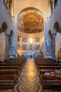 Interior of the Basilica of Santi Quattro Coronati in Rome, Italy, featuring wooden pews and the majestic apse fresco of the Glory of Paradise